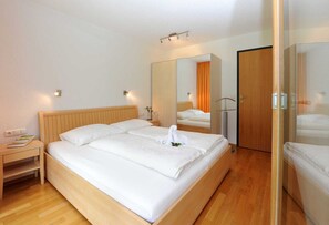 Une chambre d’hôtel avec un lit en bois, une table de chevet, un miroir et une armoire.