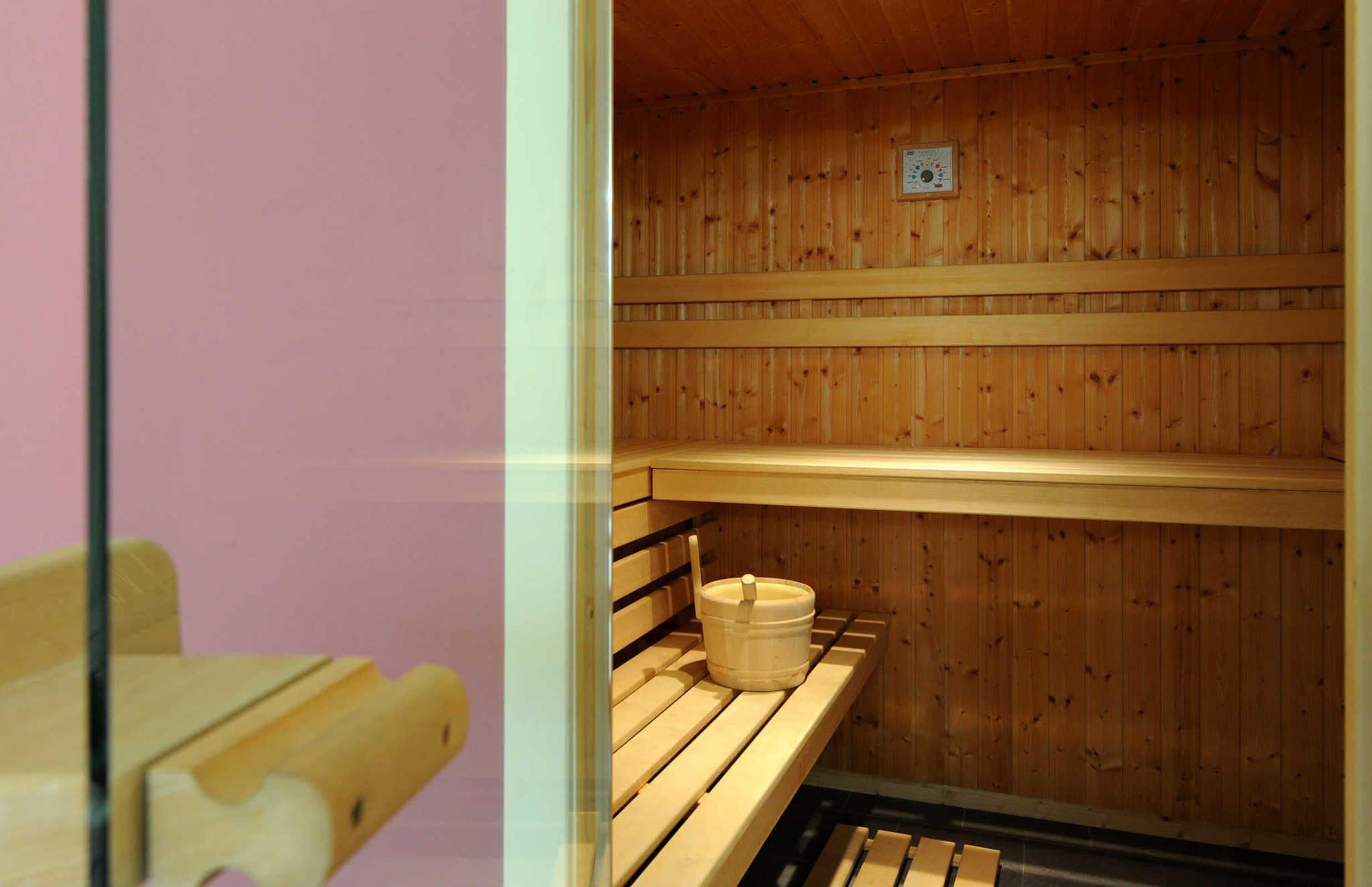 Una sauna con bancos de madera y un cubo.