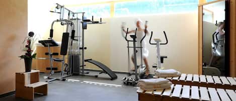 Un gimnasio con equipo de ejercicio, una banca y toallas.