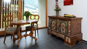 Una habitación con una mesa de comedor de madera, sillas, un armario con cuadros florales y una ventana con vistas a la vegetación.