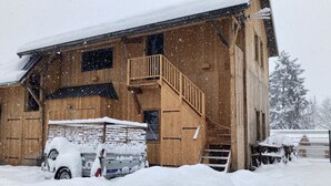 Ein hölzernes Stallgebäude mit einer Holztreppe und einem überdachten Bereich.