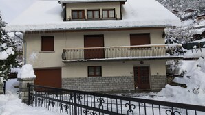 A two-story building with a snow-covered roof and a balcony with a metal railing. - Villa 130 m² near 3 valleys and spa (Salins-Les-Thermes)