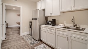 A modern kitchen with white cabinets, a stainless steel sink, and a built-in refrigerator.