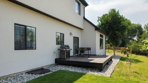 A modern house with a patio, a barbecue grill, and a small deck.