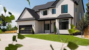 A modern two-story house with a garage, large windows, and a well-maintained lawn.