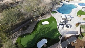 Ein Golfplatz mit Schwimmbad, Liegestühlen und einer Terrassenanlage.