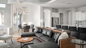 Ein modernes Wohnzimmer mit einer Eckcouch, einem Couchtisch und einem Essbereich mit Stühlen.