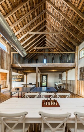 A spacious room with a high wooden ceiling, a ping pong table, and a chessboard.