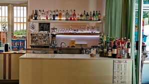 A bar area with shelves of liquor bottles, glasses, and a coffee machine. - Hotel Nanni Garnì (Rimini)