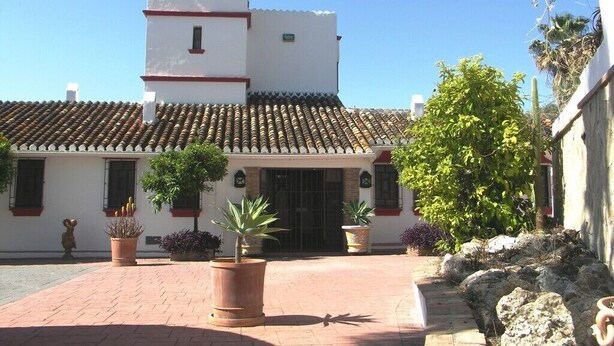 A white building with a tiled roof and a bell tower. There are potted plants and a cactus in the courtyard. - Spectacular villa with private pool and beautiful views (Nerja)