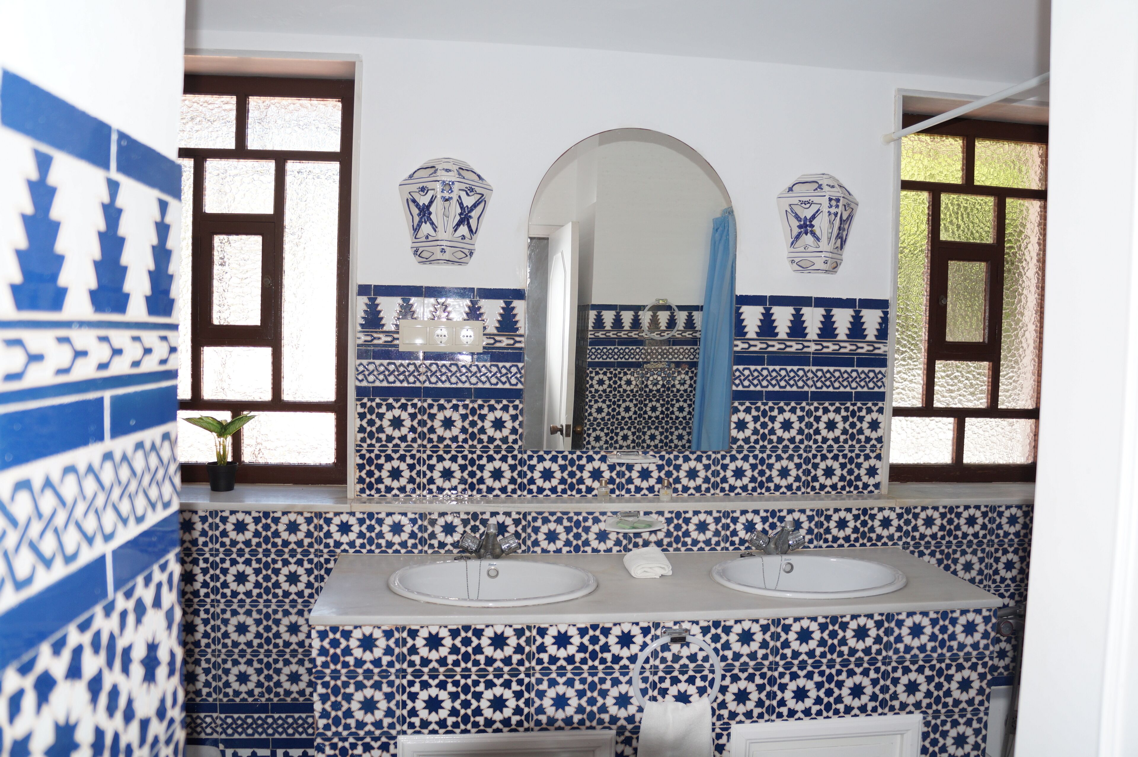 A bathroom with two sinks, a mirror, and blue and white patterned tiles.