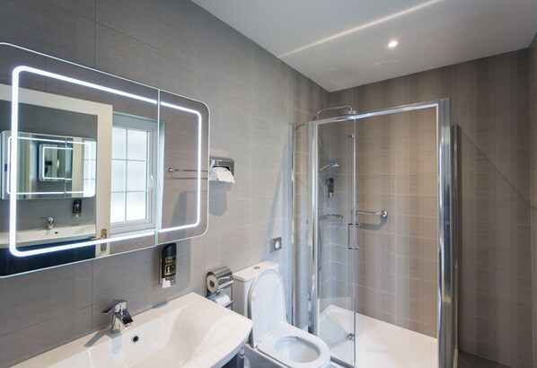 A modern bathroom with a large mirror, a bathtub, a toilet, and a glass-enclosed shower. - Luxurious Balcony Apartment Killarney Town Centre (Killarney)