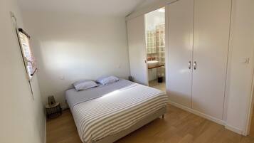 Een slaapkamer met een bed, een kledingkast en een badkamer, zichtbaar door een geopende deur.
