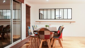 A dining area with a wooden table and colorful chairs, a sliding glass door, and a large mirror on the wall. - L'Arabesque, charming villa with private pool (Arradon)