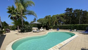 Ein Swimmingpool mit Liegestühlen und Palmen.