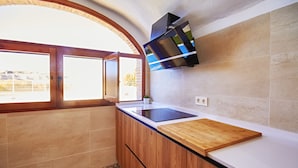 A kitchen with wooden cabinets, a black stove, and a large window with a view of a fence.