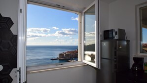 Eine Küche mit Meerblick, einem Kühlschrank und einem Fenster mit Blick auf eine Küstenstadt.