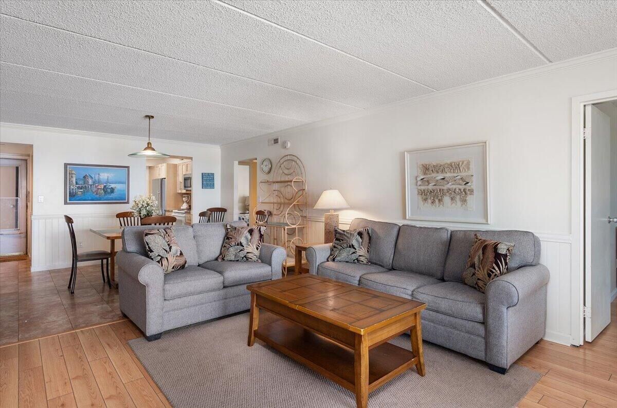 Ein Wohnzimmer mit zwei grauen Sofas, einem Holztisch und einem Essbereich mit Tisch und Stühlen.