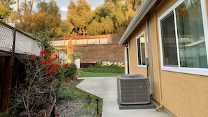 A residential area with a house, a covered outdoor area, and a garden with red flowers. - House in San Diego #1 (Lemon Grove) (Lemon Grove)
