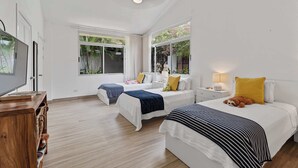 A modern hotel room with two beds, a wooden dresser, a television, and large windows with curtains. - 7 min walk to Surfing Paradise, Pool & Ocean Fun (Playa Grande)