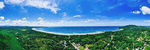 A coastal landscape with a beach, dense greenery, and a clear sky. - 7 min walk to Surfing Paradise, Pool & Ocean Fun (Playa Grande)