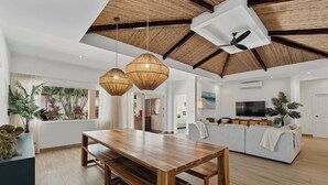 A spacious living area with a wooden dining table, a sofa, and a ceiling fan. - 7 min walk to Surfing Paradise, Pool & Ocean Fun (Playa Grande)