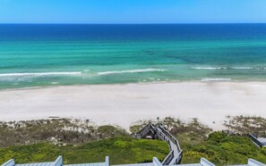 A beach view with a wooden boardwalk leading to a structure with a roof.