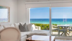 A room with a white sofa, a small table, and a view of the ocean.