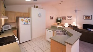 Eine kleine Küche mit Mikrowelle, Kühlschrank, Herd und einer Essecke.