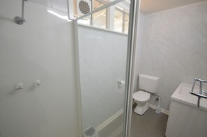 A bathroom with a glass shower enclosure, a toilet, and a sink. - Surf Caster - Kalbarri, WA (Kalbarri)