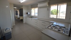 Une cuisine équipée d’une cuisinière à gaz, de meubles blancs et d’une fenêtre donnant sur l’extérieur.