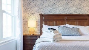 A neatly made bed with a quilted cover, a wooden headboard, and a bedside lamp on a nightstand.