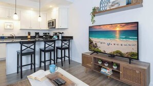 A modern kitchen with white cabinets, a black countertop, and pendant lighting.