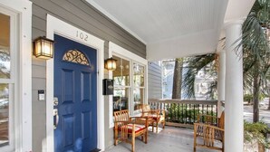 A porch with a blue door, numbered 102, and wooden chairs. - Starland Town House, Walk to the Park, 2 Parking Spaces (Savannah)