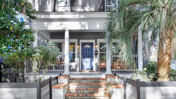 A two-story building with a blue door, a covered porch, and a brick staircase leading to the entrance. - Starland Town House, Walk to the Park, 2 Parking Spaces (Savannah)