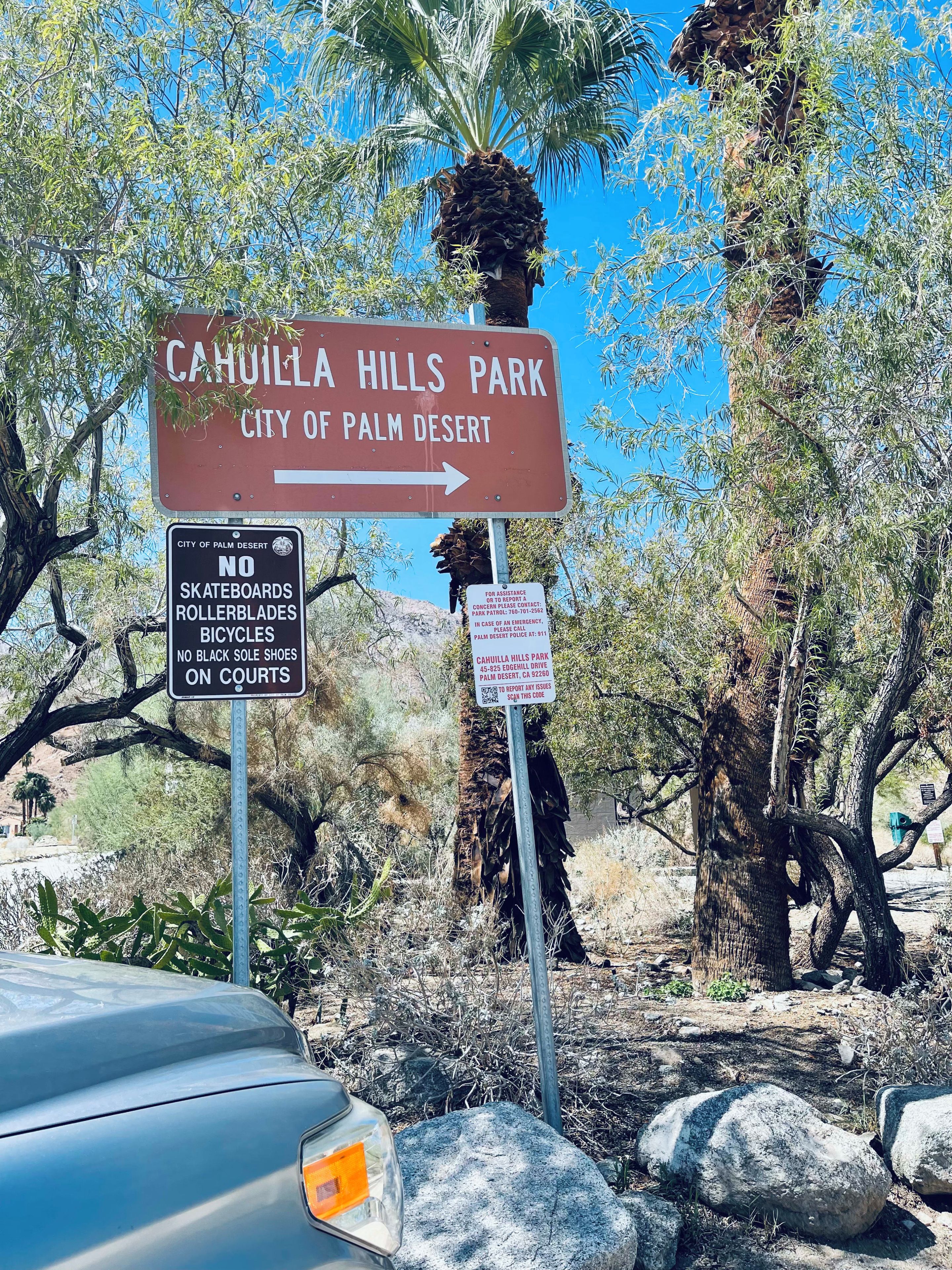 A directional sign for Cahuila Hills Park in Palm Desert, CA, with additional rules about no skateboards, rollerblades, bicycles, and black sole shoes on courts.