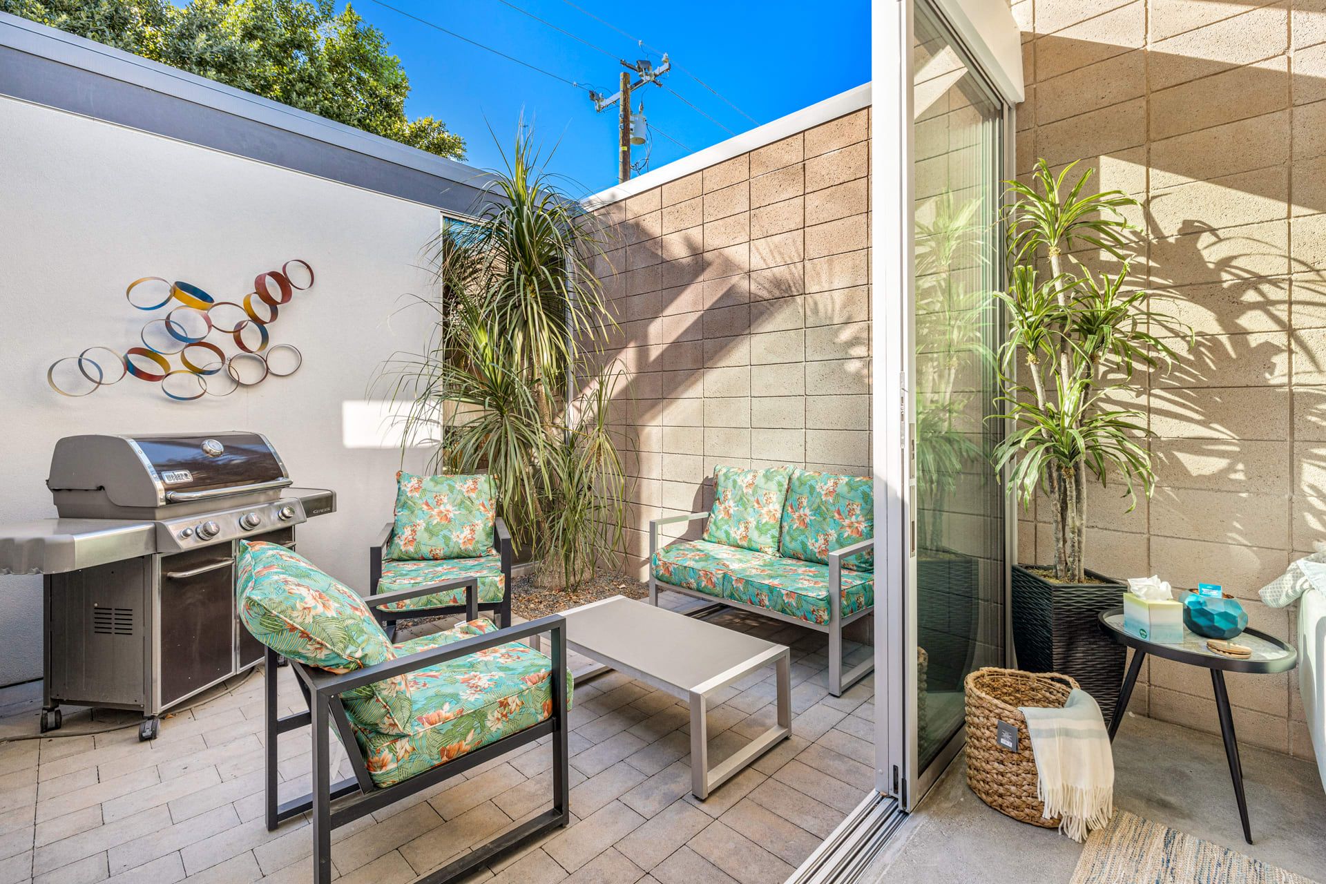 Eine Terrassenanlage im Freien mit Grill, zwei Stühlen, einem Tisch und Kübelpflanzen.