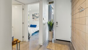 A hallway with a bed, a potted plant, and a textured rug. - Palm Desert Velo - Modern Condo w Spa (Palm Desert)