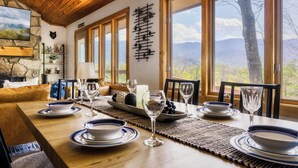 Un comedor con una mesa de madera dispuesta para cuatro, ventanas amplias y vistas al exterior.