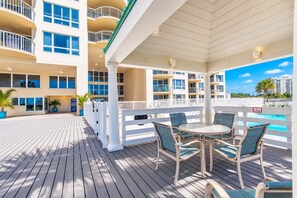 Un espace extérieur abrité comprenant une piscine, des rampes blanches et une table avec des chaises.