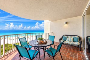 Un balcon avec une table ronde, des chaises et un canapé avec des coussins.