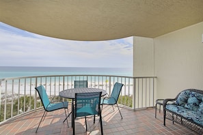 Un balcon avec vue sur la plage, une table ronde avec des chaises et un canapé en osier.