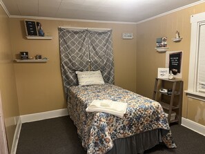 Relax in this serene bedroom with a floral-patterned bed and geometric headboard, perfect for unwinding.