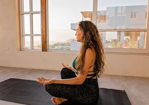Guests can practice yoga or meditation in a peaceful space with a large window offering a view of the surrounding area.