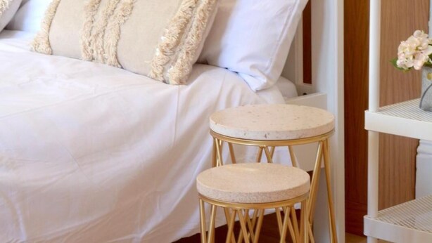 A bed with white bedding and two beige pillows, a round table with a marble top, and a wooden floor. - Remarkable 1 Bed Apartment in Birmingham (Birmingham)