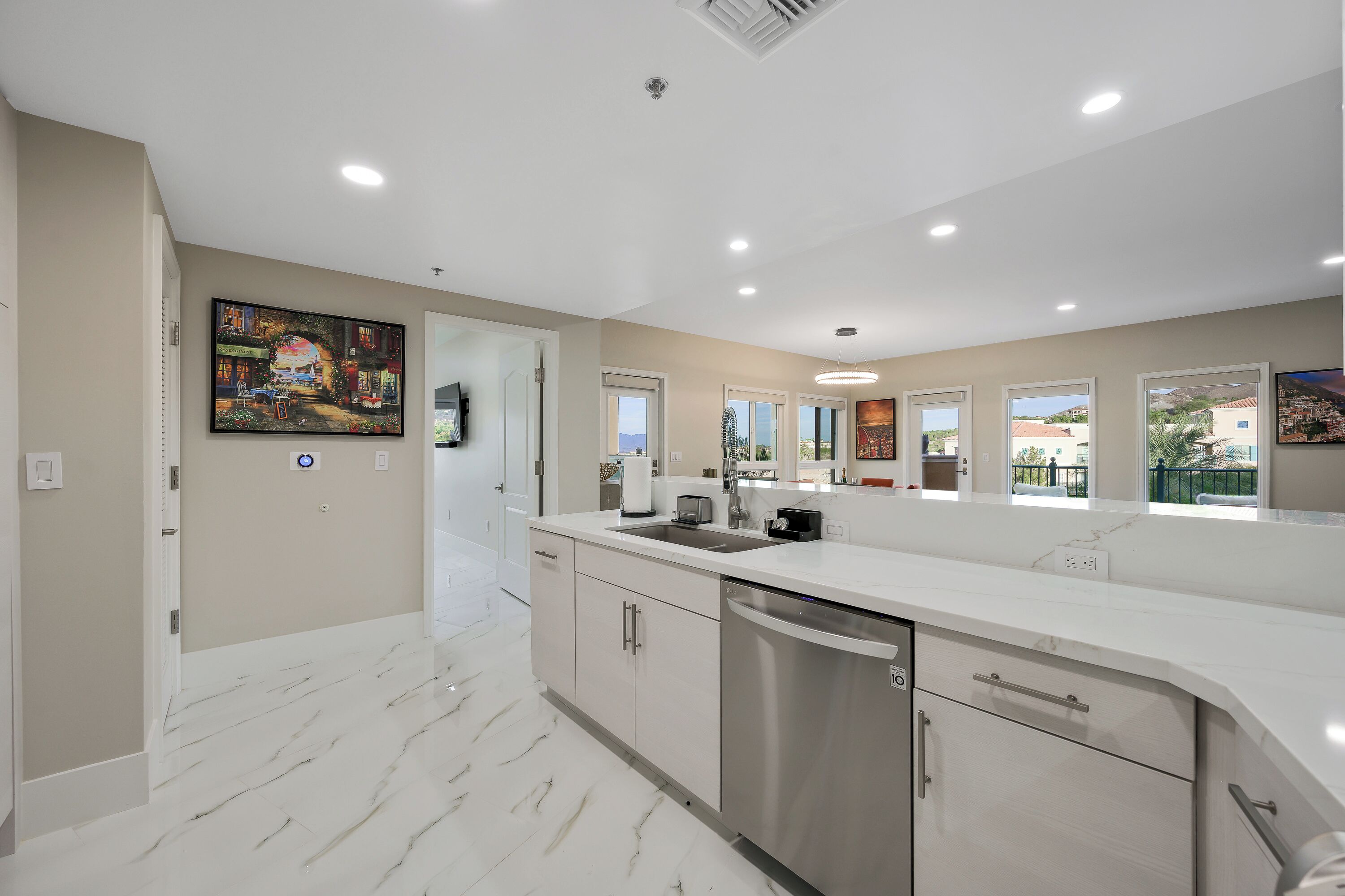 A modern kitchen with white cabinetry, a stainless steel dishwasher, and a marble floor.