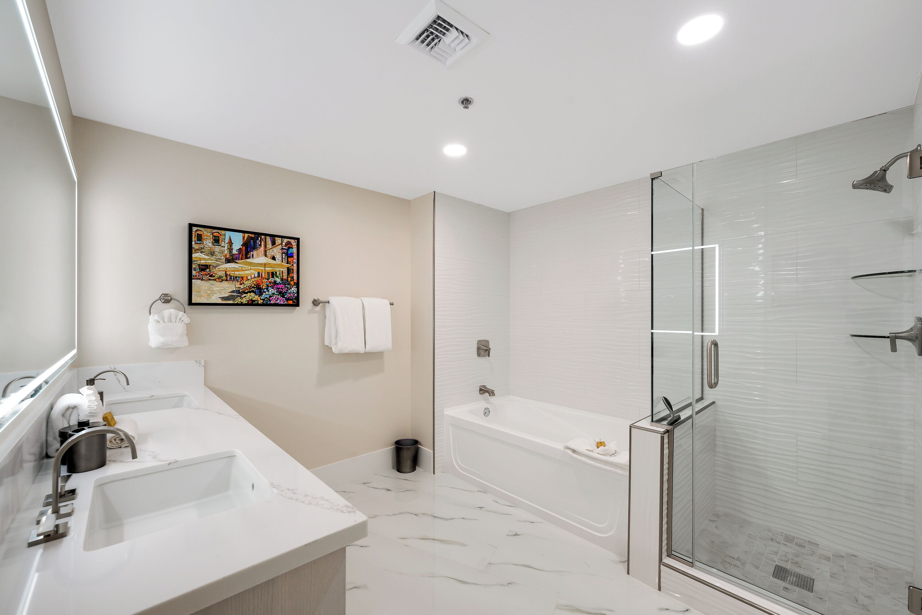 Un baño moderno con lavamanos doble, ducha con cerramiento de vidrio y suelo de mármol.