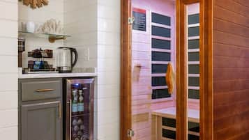 A room with a sauna, a coffee machine, and a small cabinet.