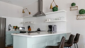 Une cuisine moderne dotée d’un îlot central, de tabourets de bar, d’un réfrigérateur en acier inoxydable et d’un four encastré.