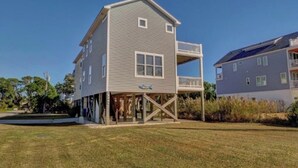 A two-story building with a balcony, a covered area, and a visible sign. - Spacious and Bright townhome, steps to the beach, pet friendly* (Carolina Beach)